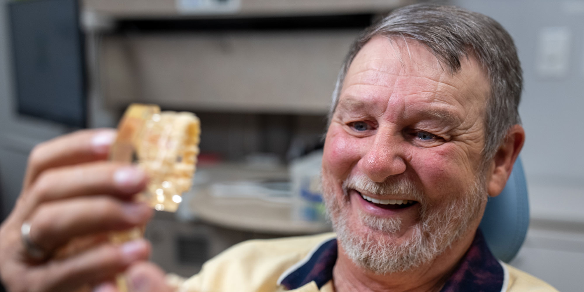 patient holding a full arch dental implant model within the dental center