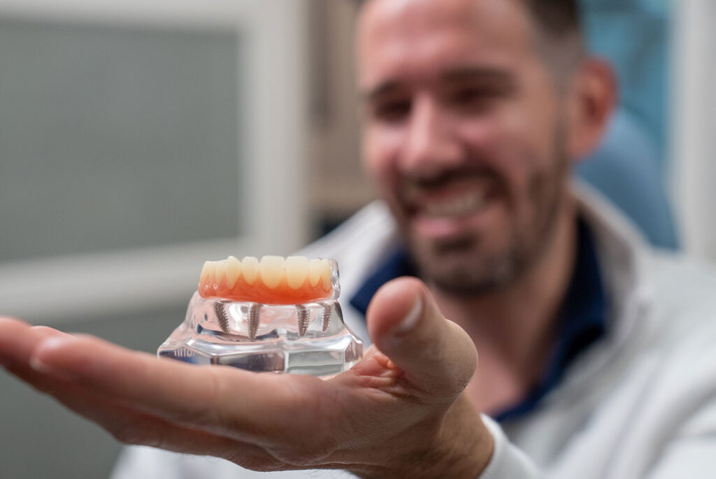 close up of dental patient holding a dental implant model