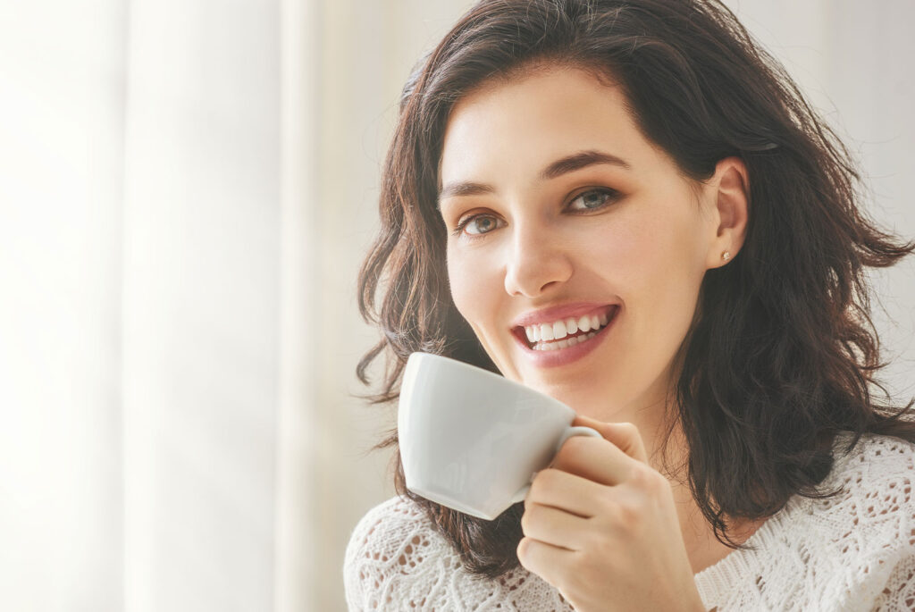 female smiling brightly with a drink their hand
